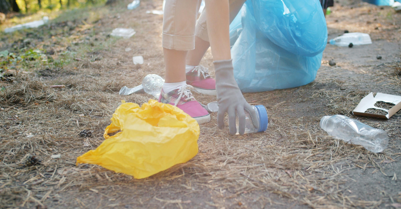 gloved hand reaching down to clean up litter
