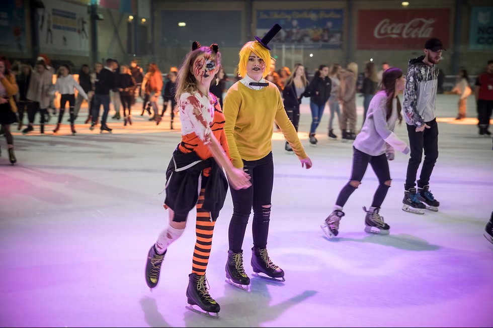 Children skating on indoor rink in Halloween costumes. 