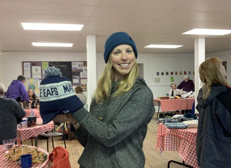 Smiling woman holding up a toque in a community hall