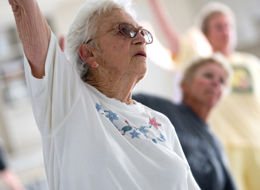 Older woman reaching arm up in group fitness class