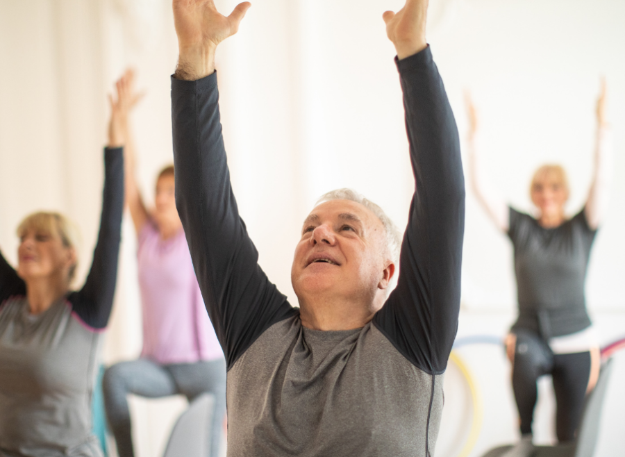 group exercise class with man in focus with arms up