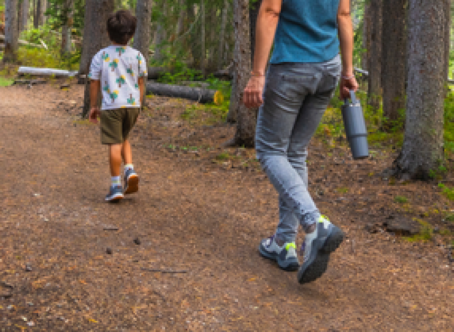 boy and woman walking on forest trail