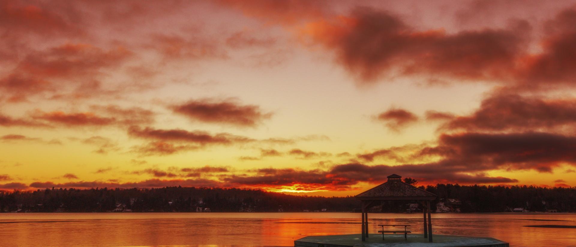 Lake with gazebo at the end of dock sunset sky 