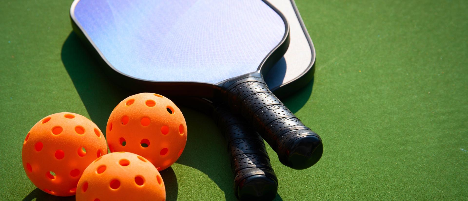 Pickleballs and paddles lying on a green surface