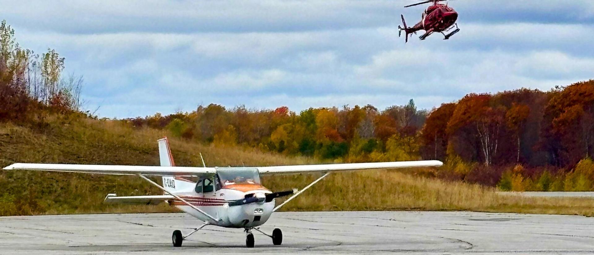 A landed airplane and a helicopter flying overhead