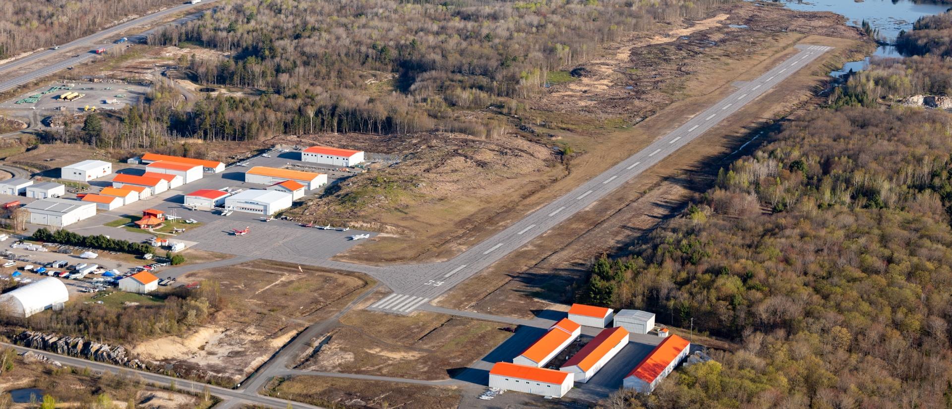 Older version of the airport runway is shown with dry cracked pavement surrounded by brown foliage and trees