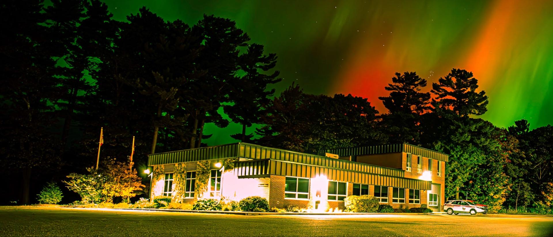 Seguin Township municipal office shown at night with northern lights shown in the sky above